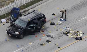 A law enforcement officer looks over the evidence near the remains of a SUV involved in the Wednesdays attack is shown in San Bernardino, California